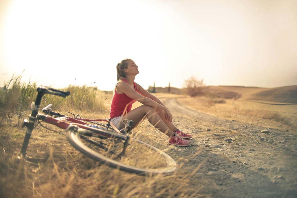 Woman sitting next to a mountain bike in a meadow