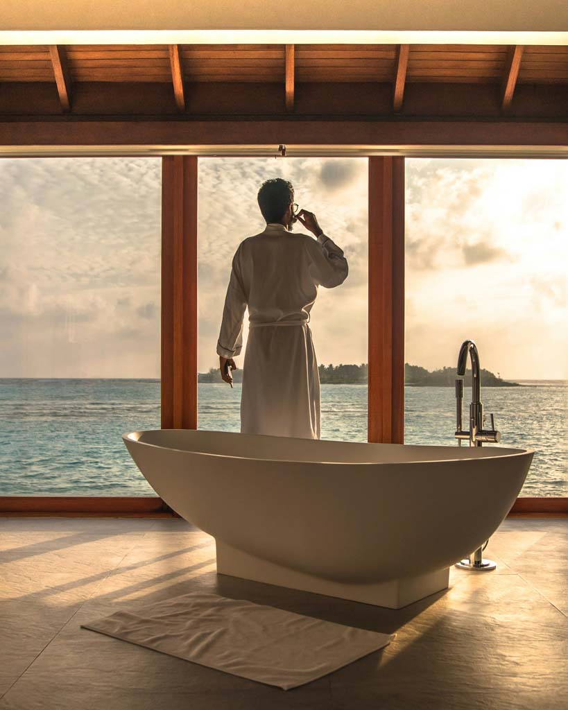 Bathtub with well dressed man looking out large window